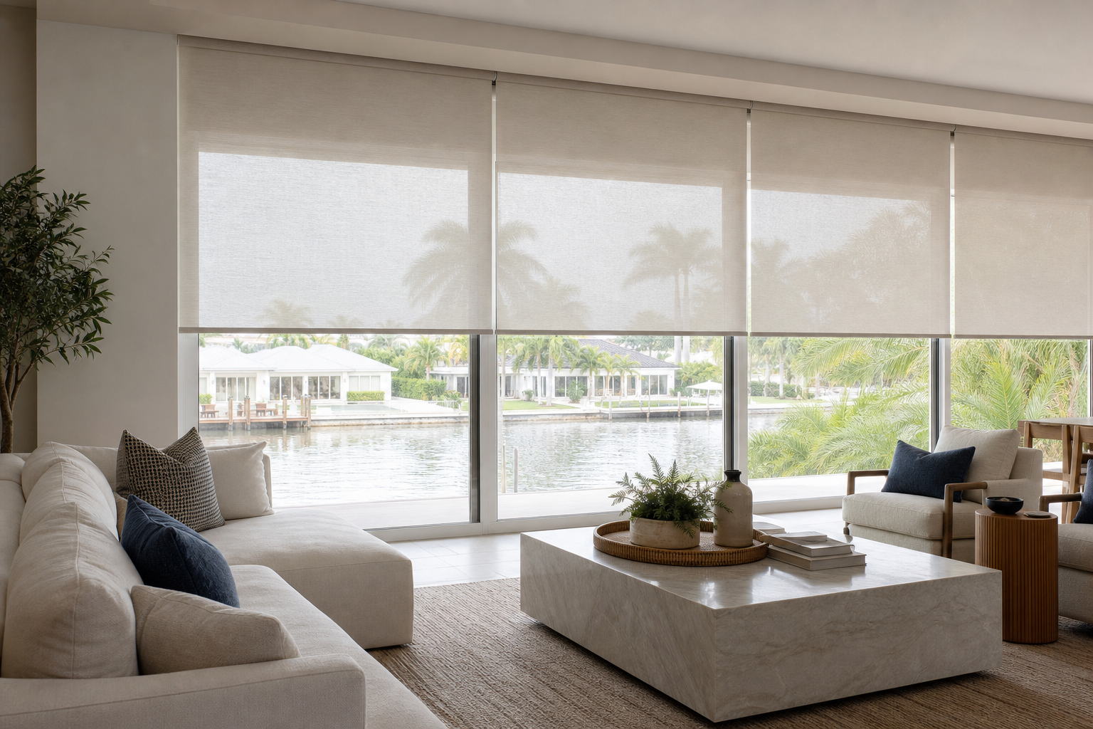 Motorized roller shades covering large living room windows in a bright South Florida home
