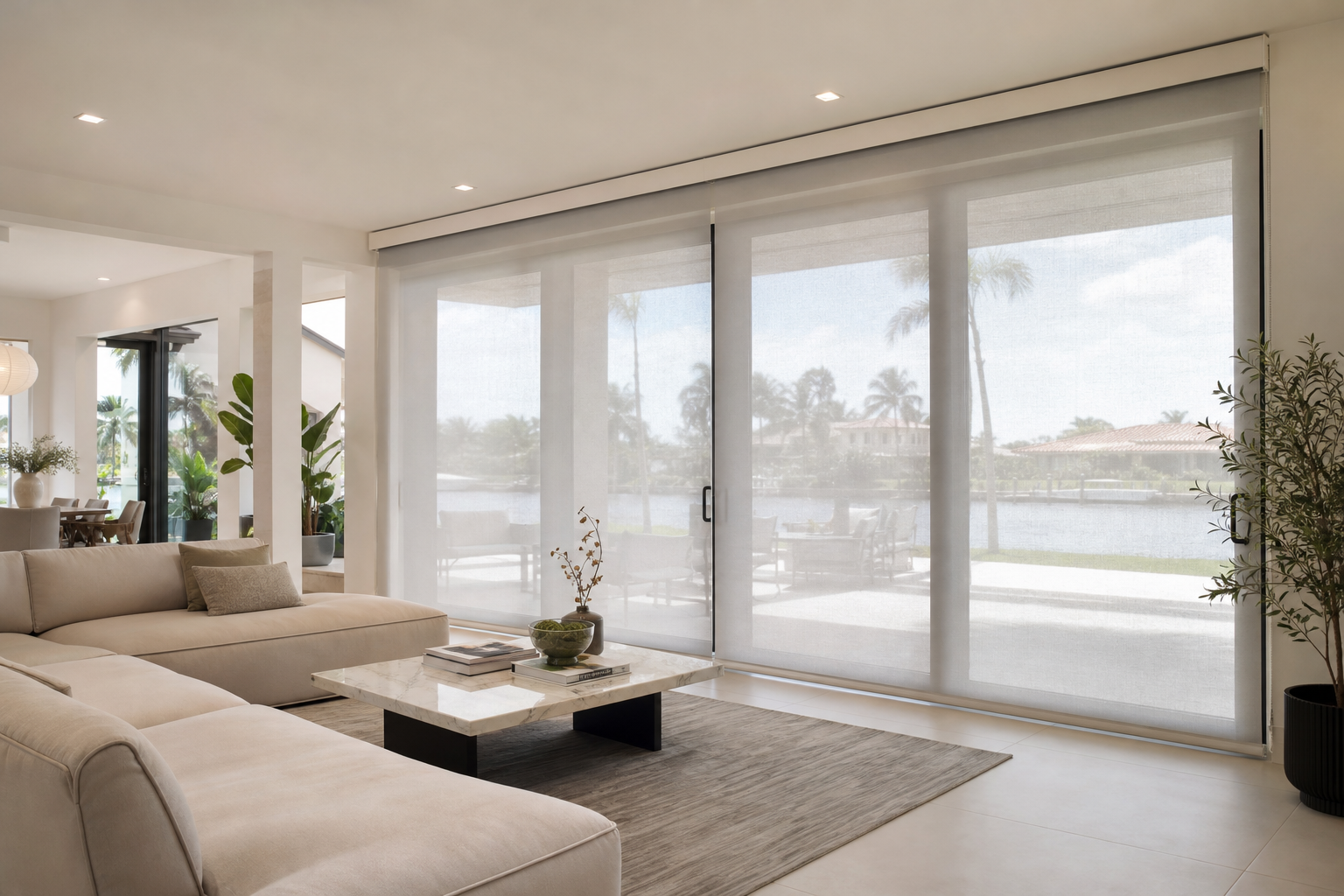 Custom motorized shades covering large sliding glass doors in a bright South Florida living room